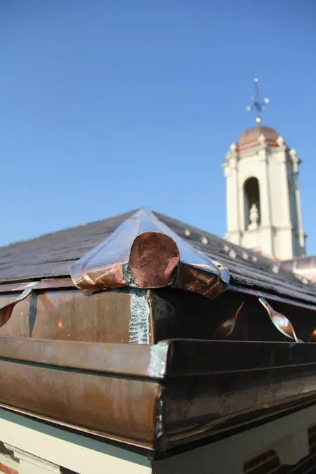 Copper-flashed roof edge below a white bell tower cupola