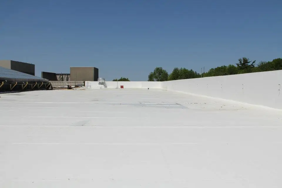 A wide field of new white single-ply membrane on a flat commercial roof