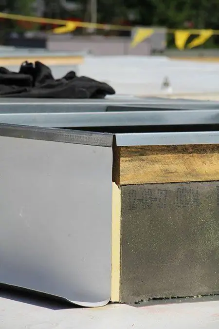 Close view of metal edge flashing turned down over black roof membrane